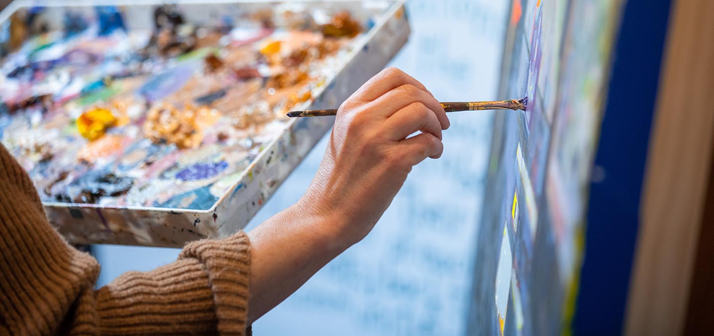 Closeup of an artist's hand painting on a canvas