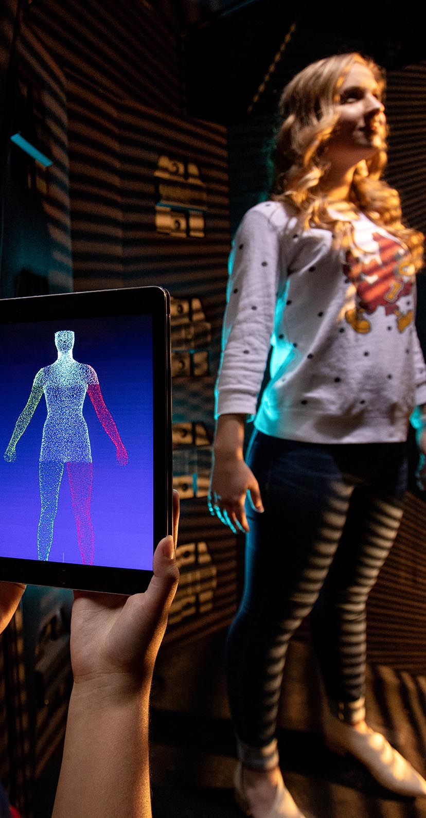A tablet shows the results of a digital body scanner with the subject in sight