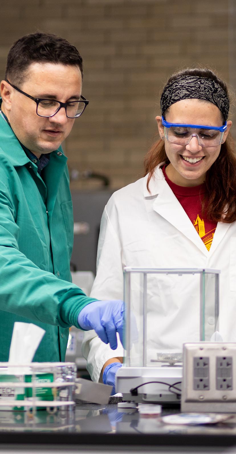 Two students work on equipment in a science lab