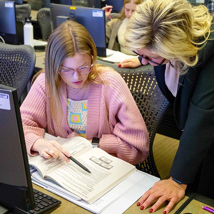 Business student and an instructor consult a workbook.