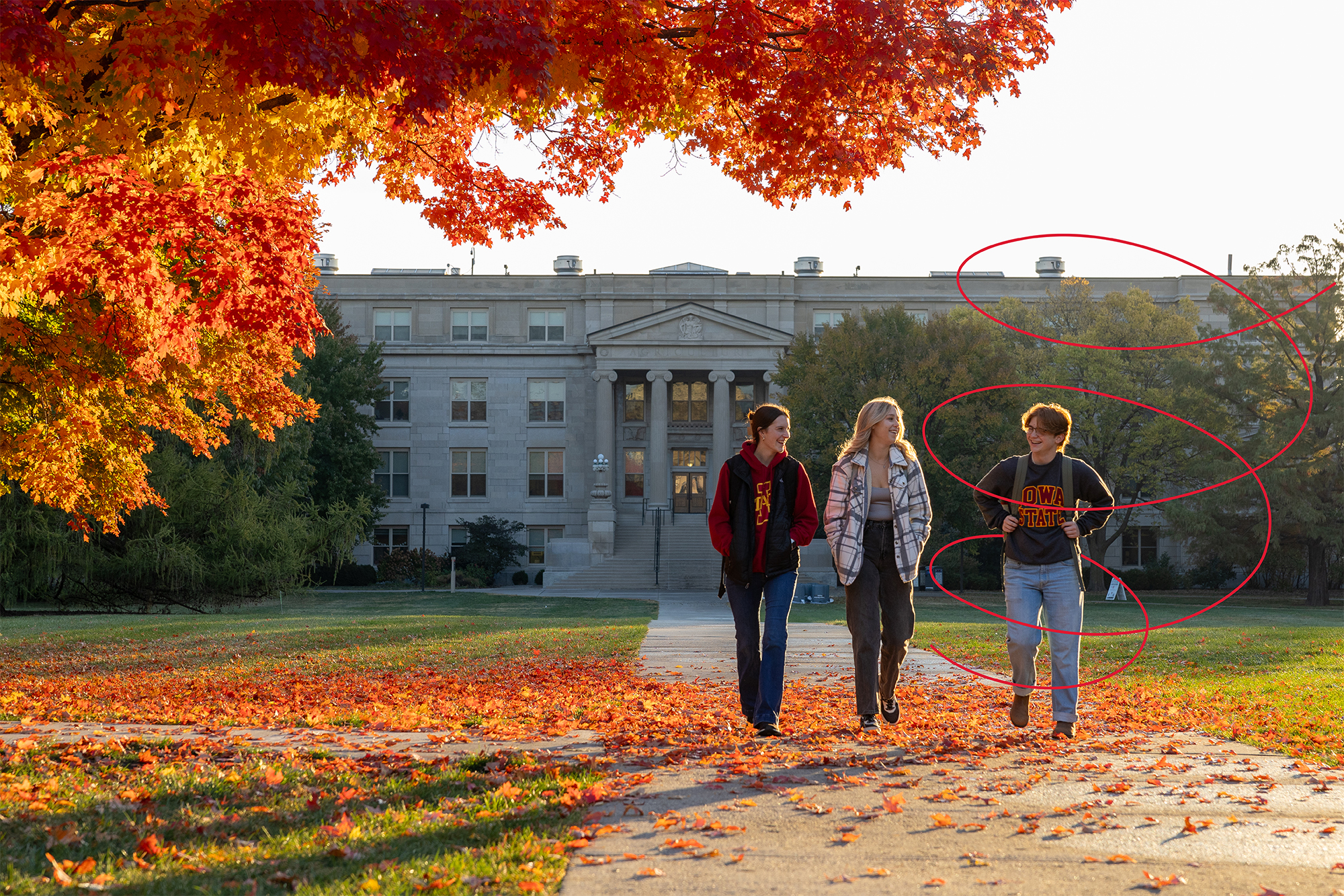 Three students walk on central campus on a fall day.