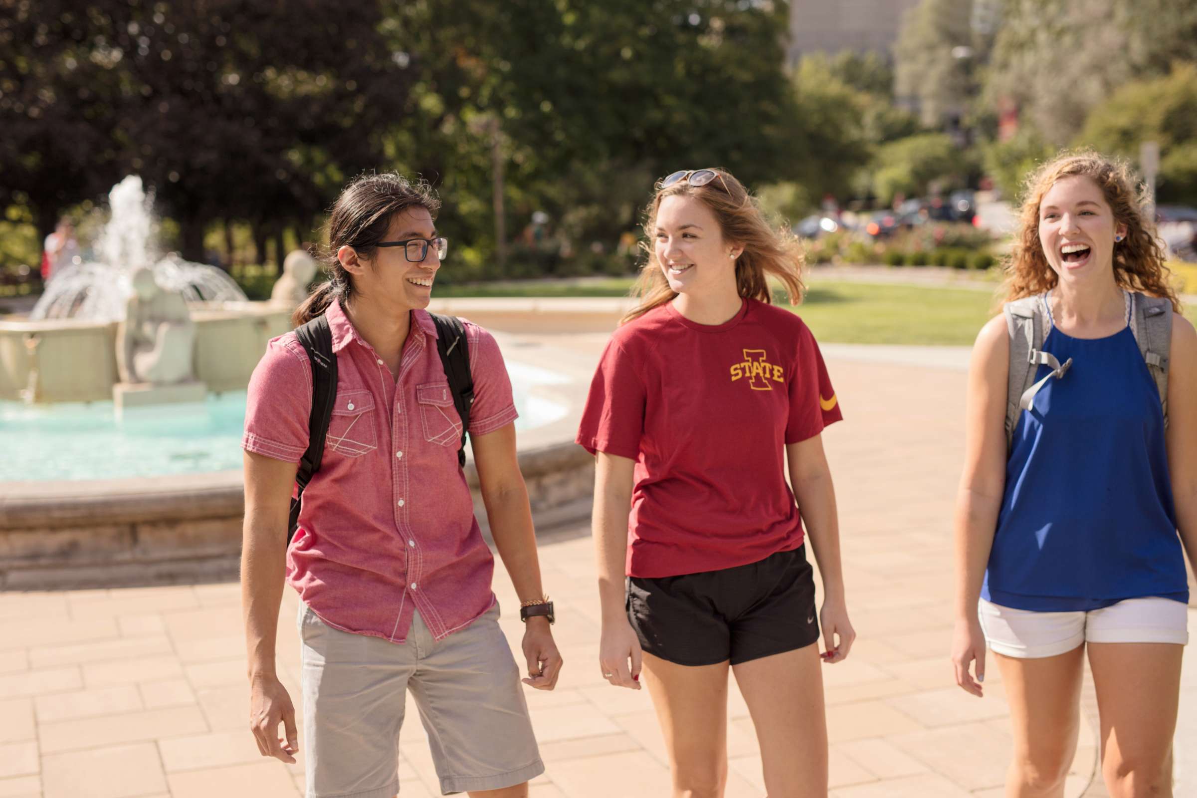 Three students walking by the Fountain of the Four Seasons in front of the Memorial Union