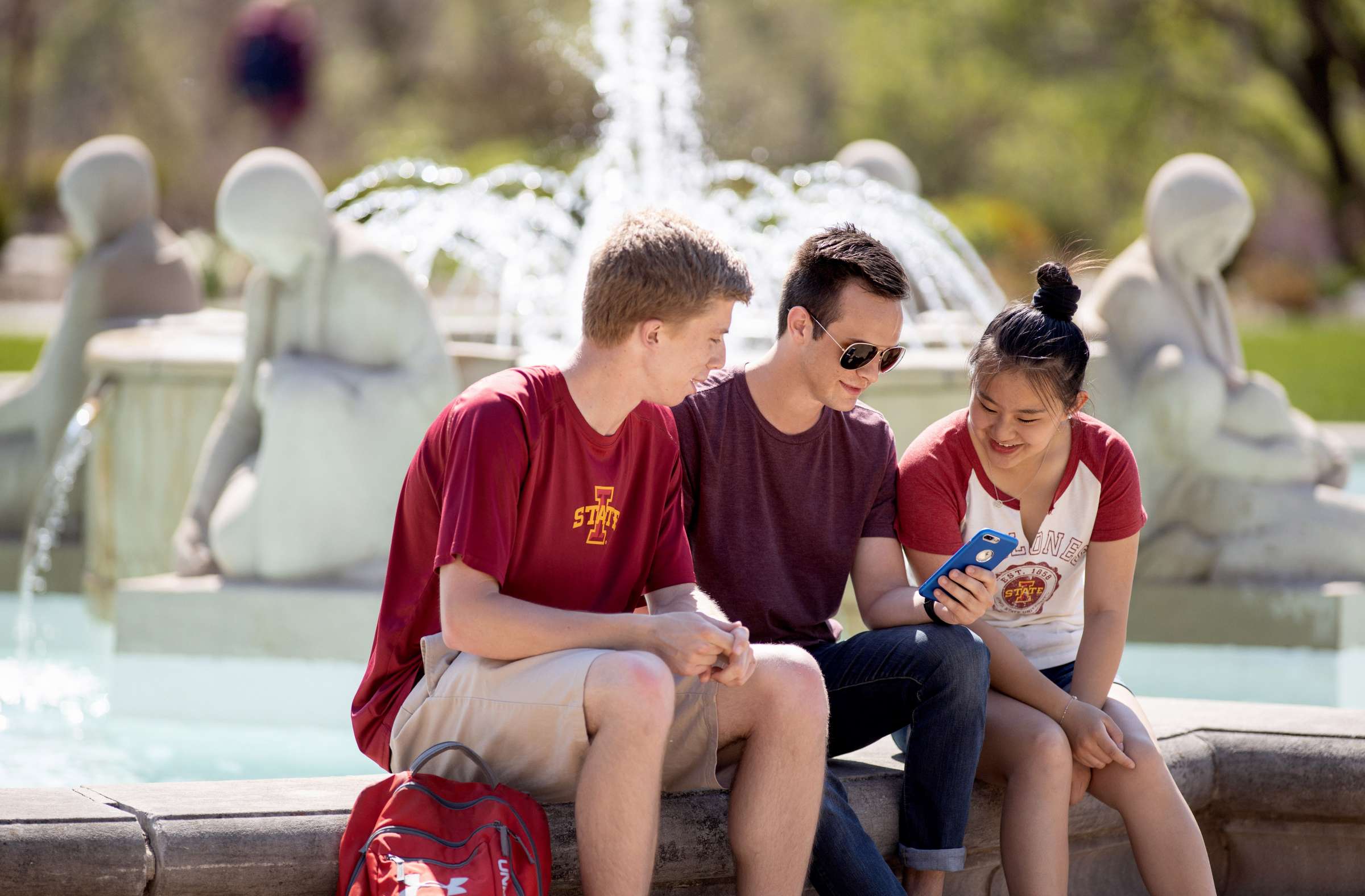 Three students sitting by Fountain of the Four Seasons in front of the Memorial Union