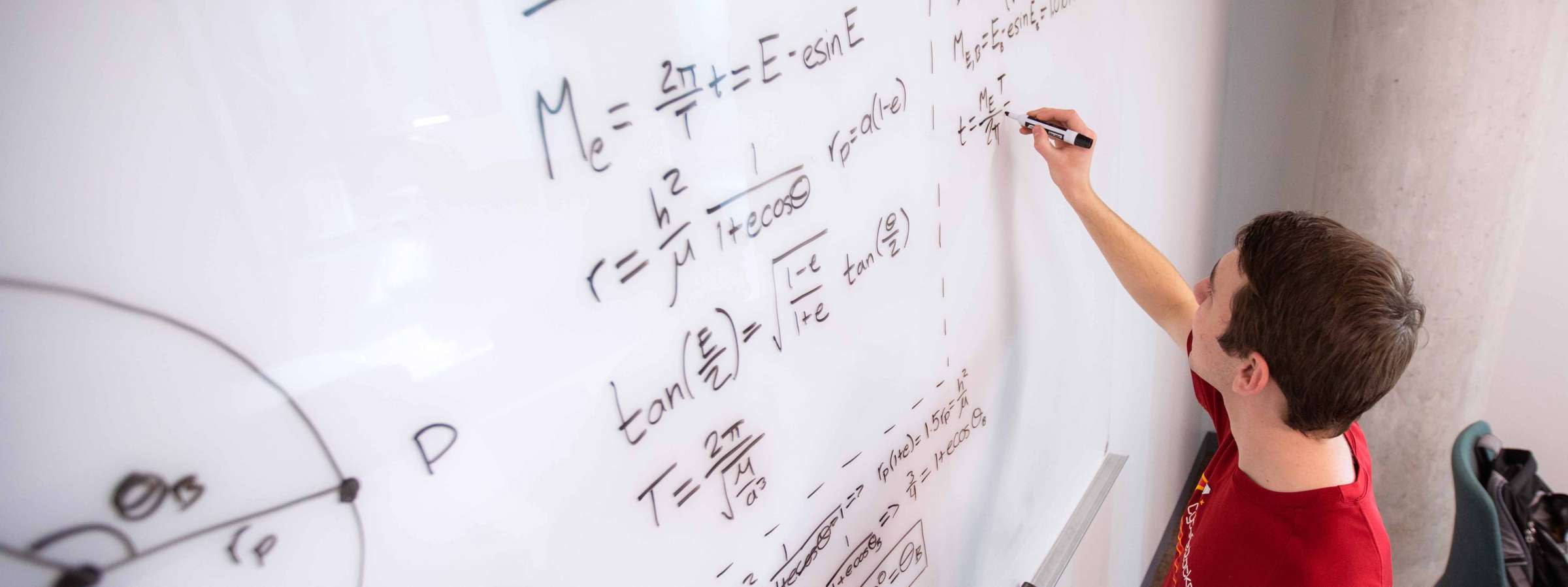 A student works equations on a white board